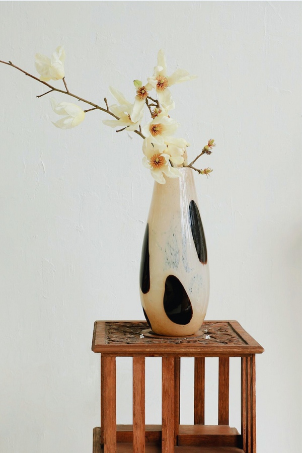 Wooden stool with black vase and dried branches for minimalist style.