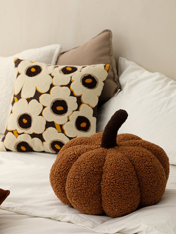 Brown pumpkin-shaped cushion on bed. | Brun pumpaformad kudde på säng.