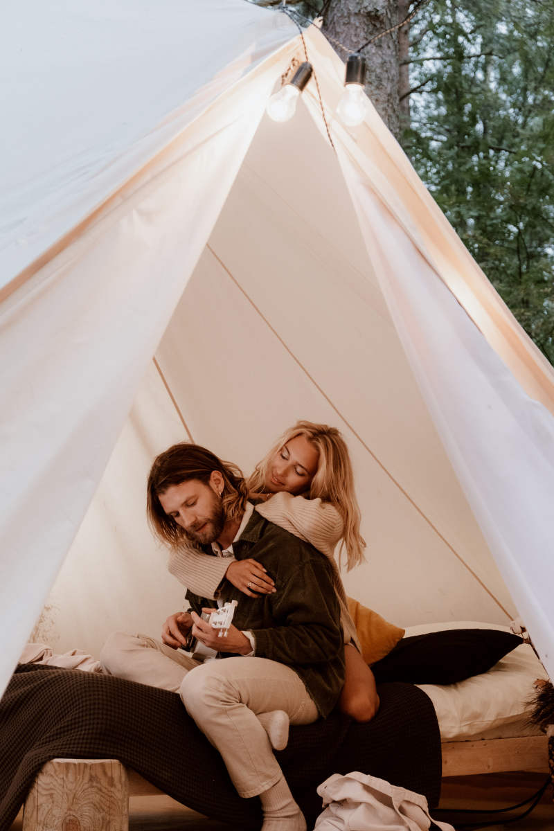 Couple cuddling in a tent, sharing a moment of intimacy and love in the outdoors.