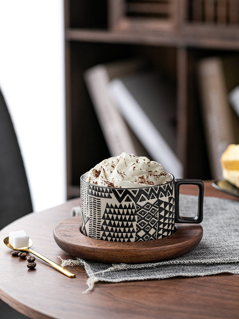 Black coffee cup with cream on wooden table. | Svart kaffekopp med grädde på träbord.