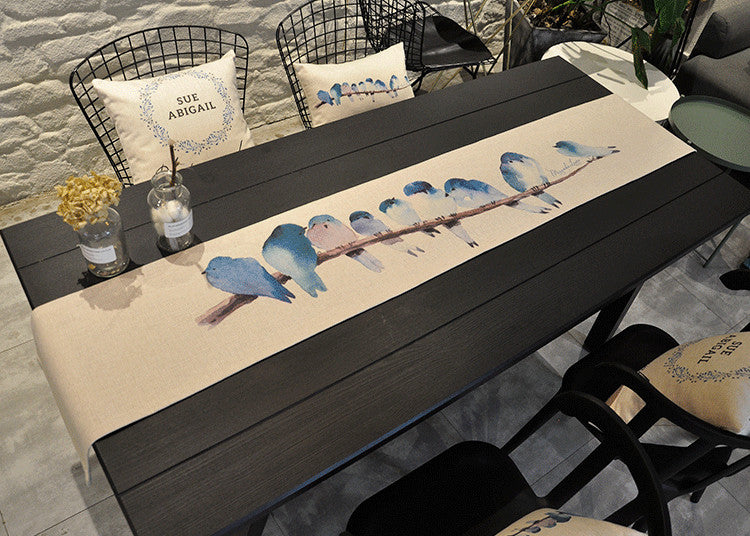 Tablerunner on black table, depicted flock of bluebirds. | Bordslöpare på svart bord med avbildad flock av blåfåglar.