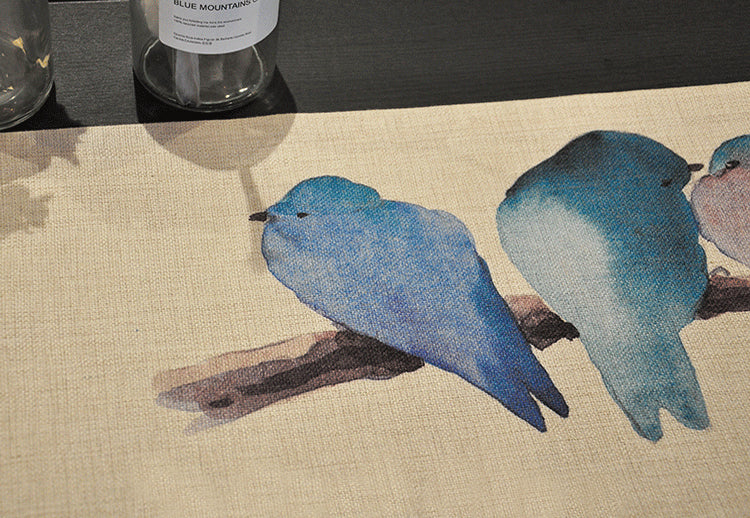 Close-up of bluebird on cream tablerunner. | Närbild av blåfågel på krämfärgad bordslöpare.