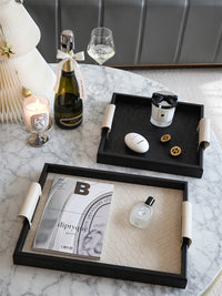 Woven leather trays, cream and black on table with champagne. | Vävda läderbrickor, kräm och svart på bord med champagne.