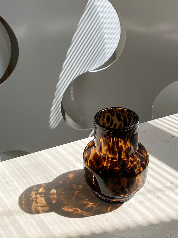 Small glass vase, leopard texture, sunlight shining through. | Liten glasvas, leopardtextur, solljus skiner igenom.
