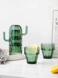 Cactus-shaped green glass cup on white table. | Kaktusformat grönt glas på vitt bord.