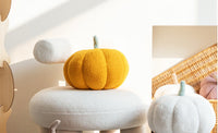 Orange pumpkin-shaped cushion in living room. | Orange pumpaformad kudde i vardagsrum.