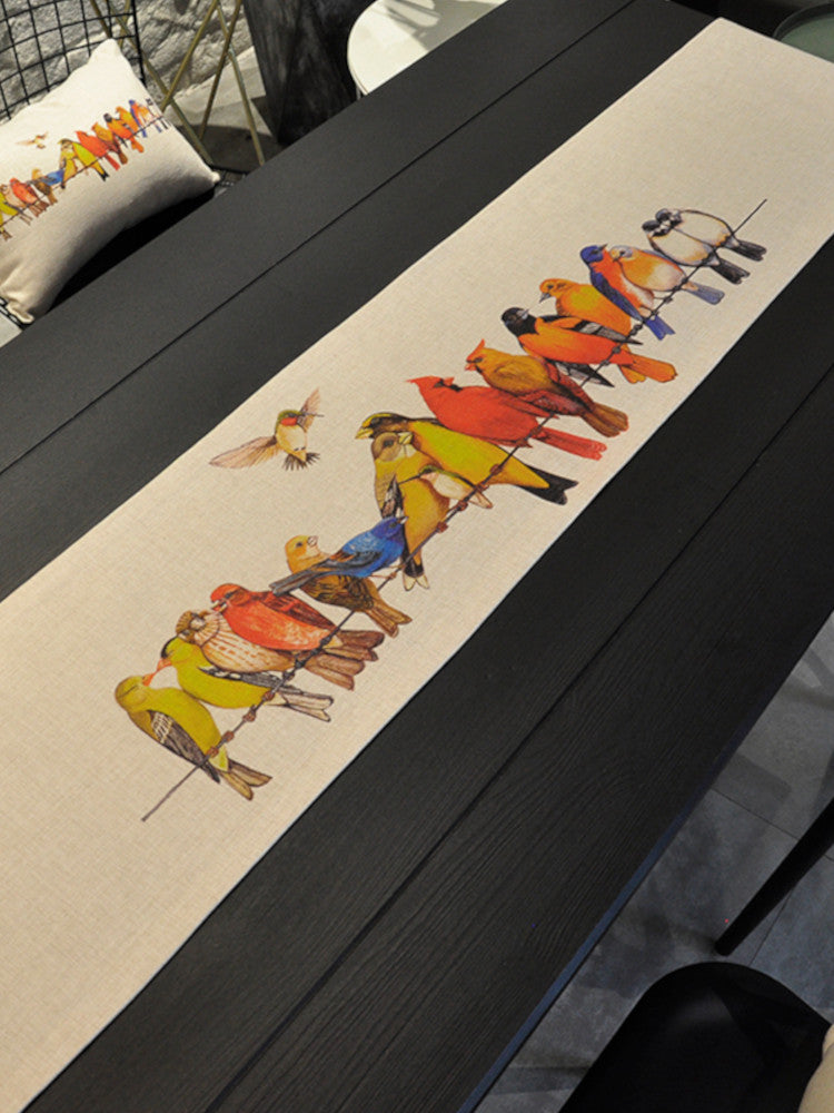 Tablerunner on black table, colorful canary flock depicted. | Bordslöpare på svart bord, färgglad kanarieflock avbildad.