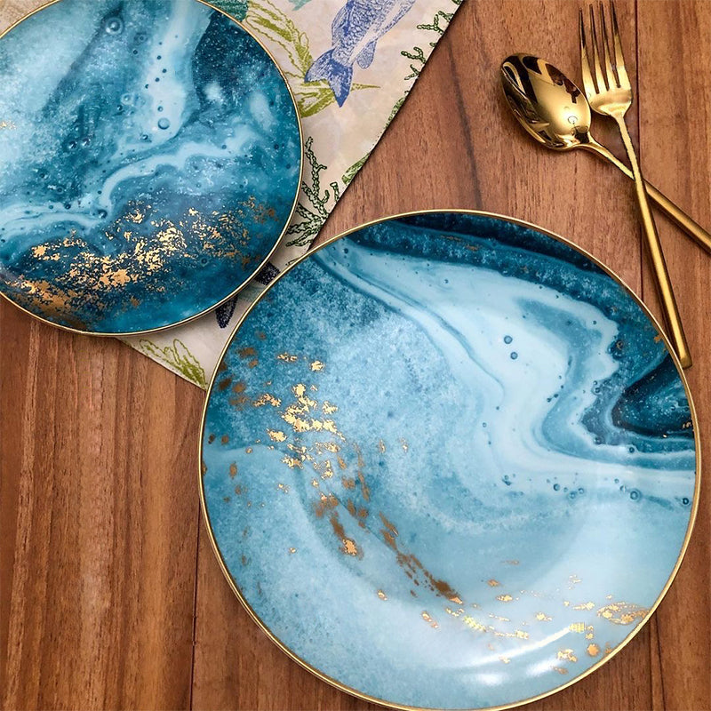 Blue marbled plates, gold speckles, elegant cutlery. | Blå marmorerade tallrikar, elegant bestick.
