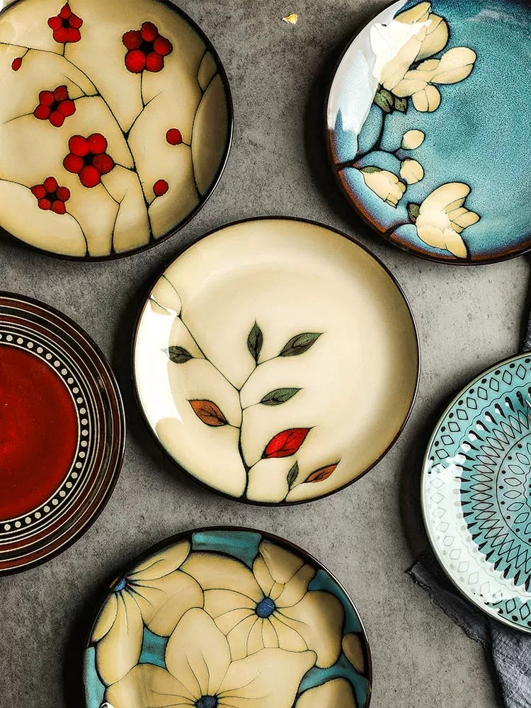 Collection of decorative plates, various floral designs, textured surface. | Samling av dekorativa tallrikar, olika blommönster, texturerad yta.