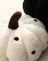 White pumpkin-shaped cushion with black dots. | Vit pumpaformad kudde med svarta prickar.